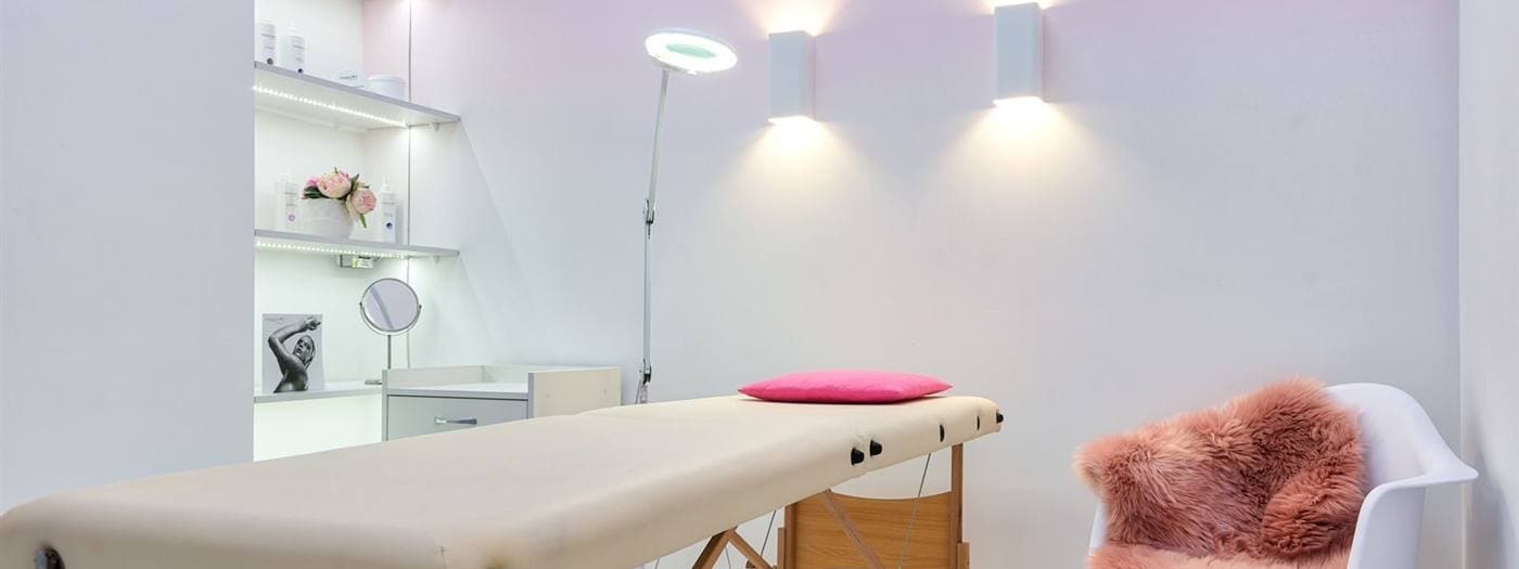 Interior claro de salão de estética com poltrona e maca de atendimento